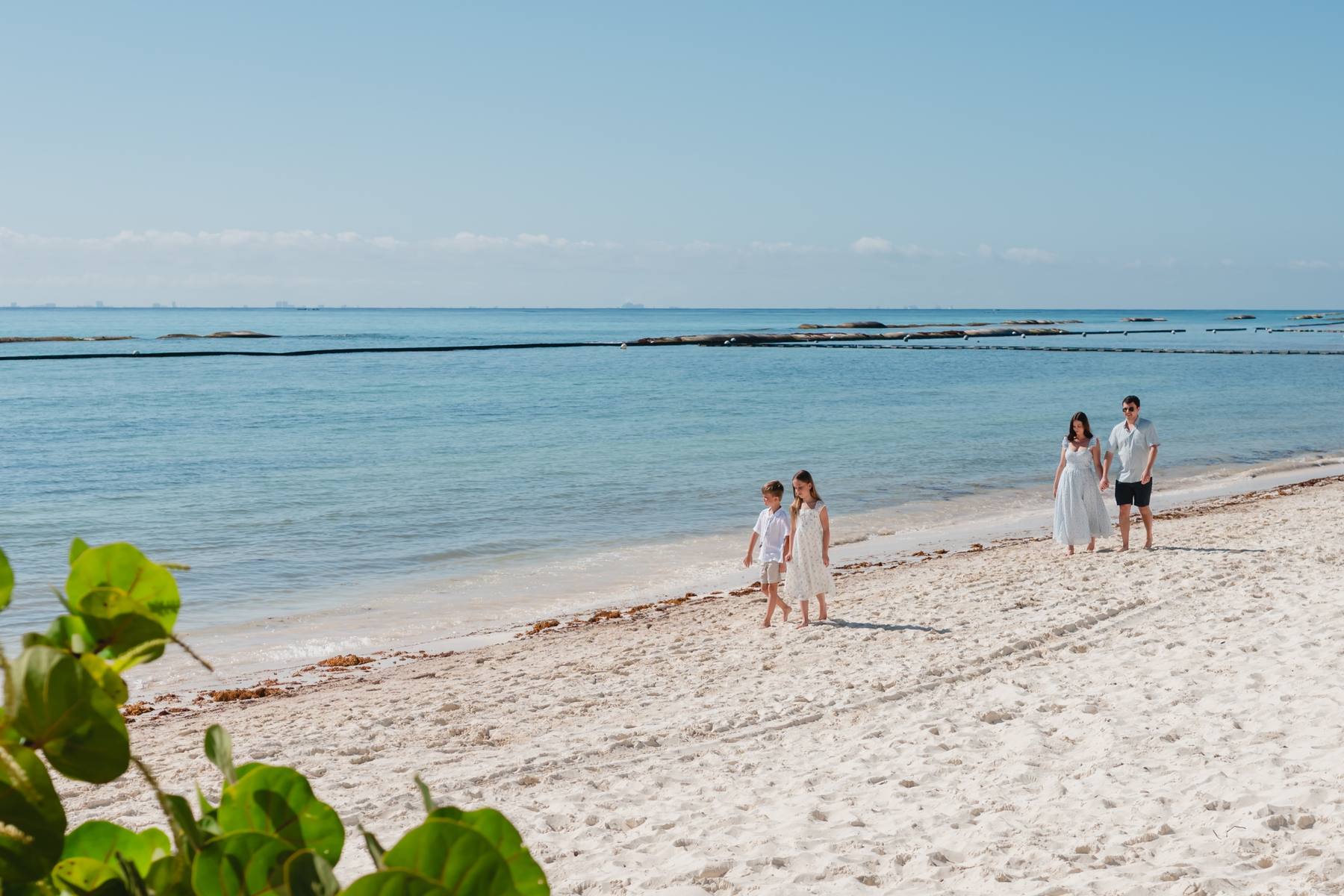 Kristina and her family walking along a white-sand beach