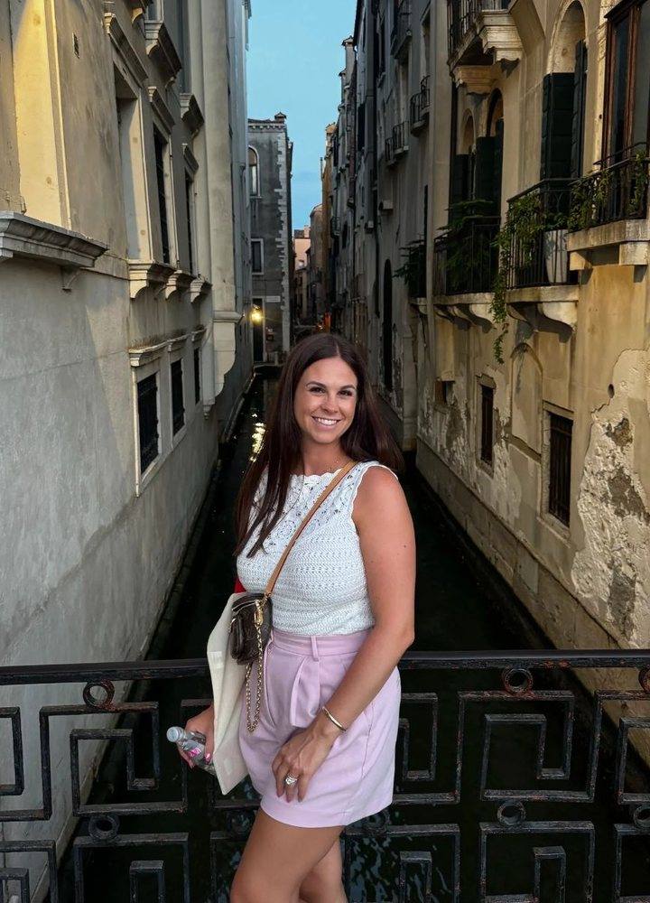 Kristina smiling on a bridge over a Venice canal
