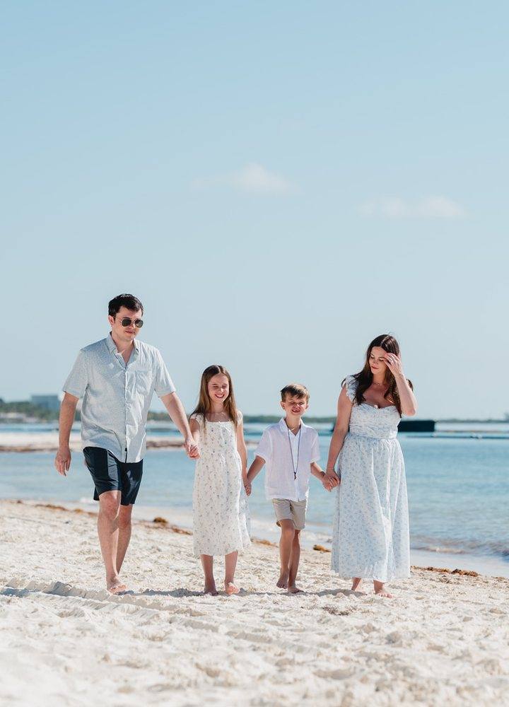 Kristina walking the beach hand in hand with her husband and two kids