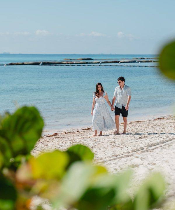 Kristina and her husband walking the beach, framed by sea grape leaves